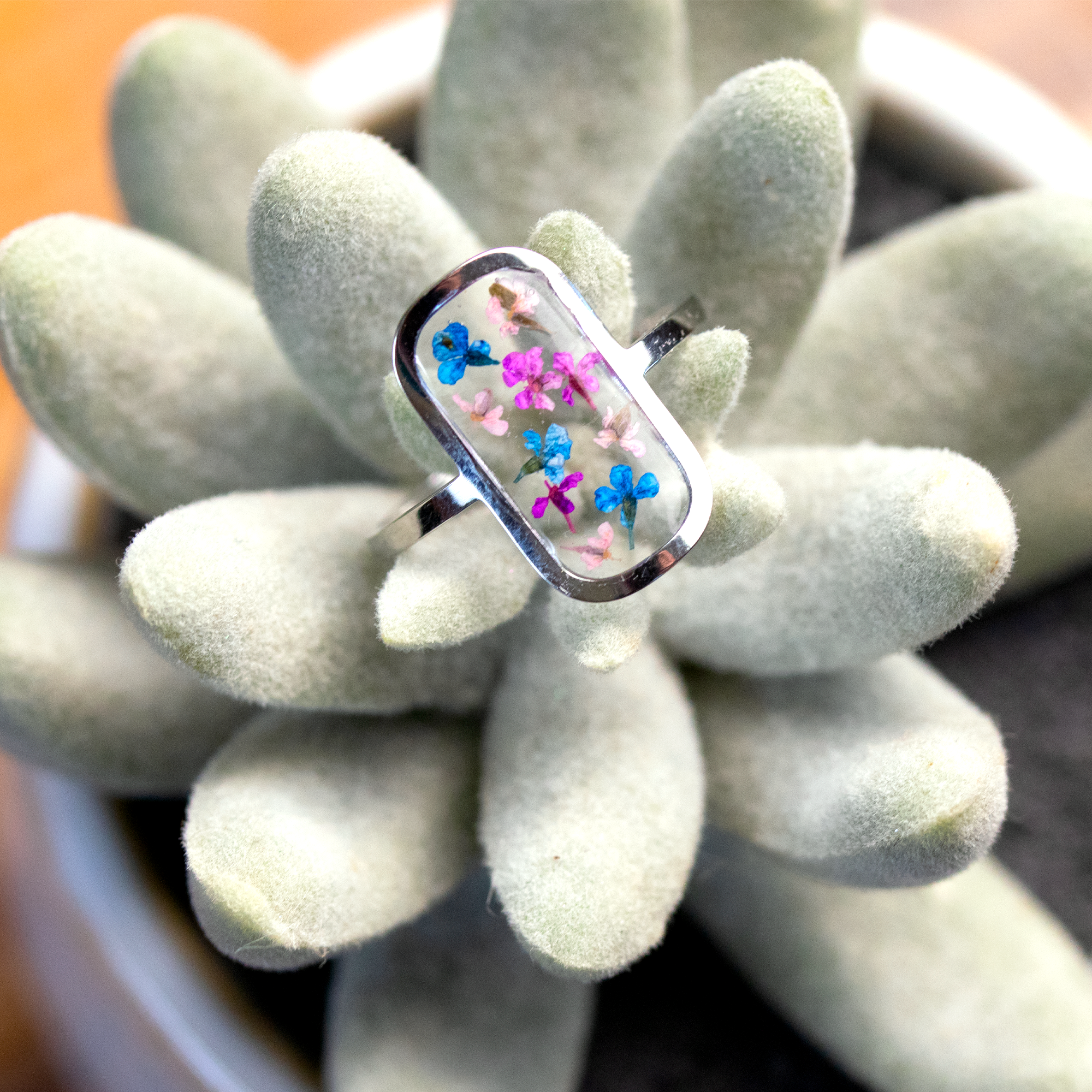 Tiny colorful flowers in silver rounded rectangle frame ring.png