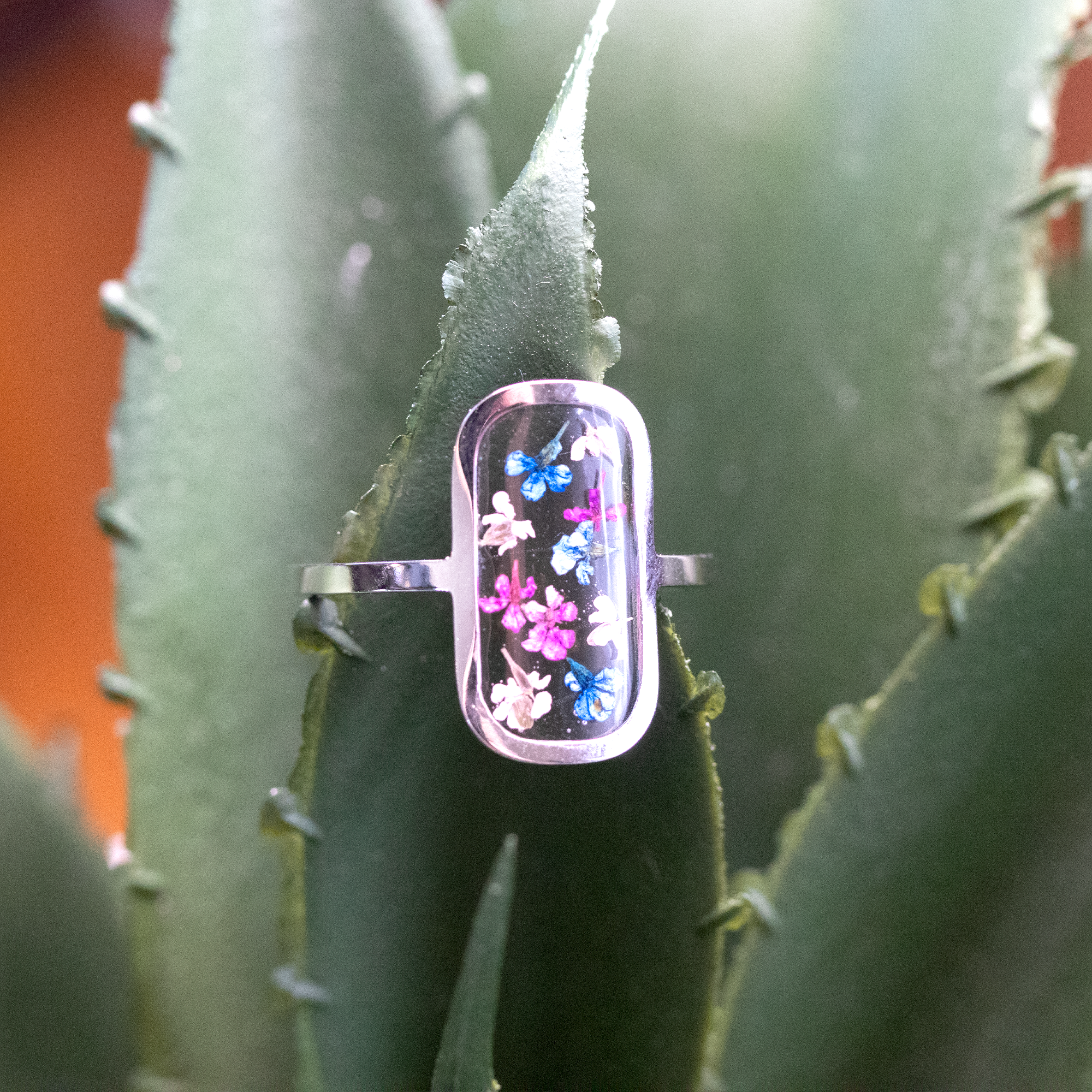 Tiny colorful flowers in silver rounded rectangle frame ring 1.png